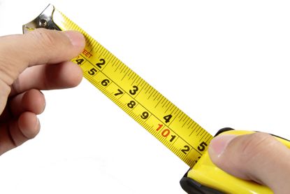 A person's hands holding an open yellow measuring tape. The image represents a rule of thumb.