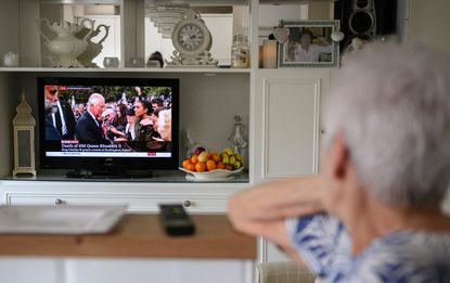 A resident watches King Charles on TV
