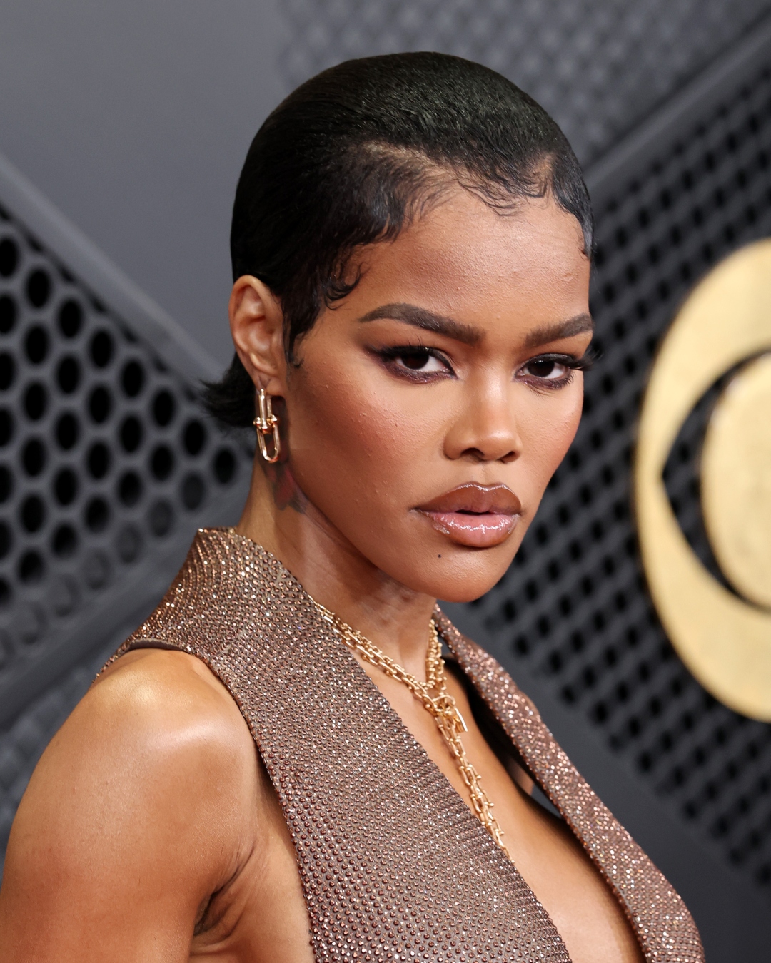Teyana Taylor with a slicked-back pixie cut and bronzed skin