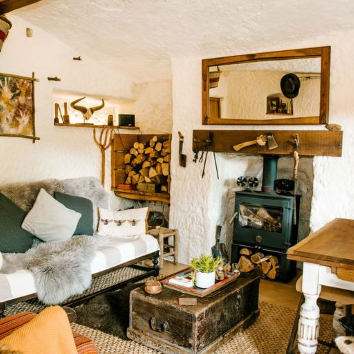 The living room includes a fireplace with a wooden beam, white sofa and wooden chairs