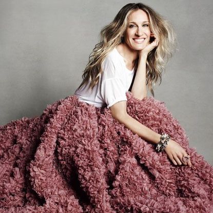 Sarah Jessica Parker smiling, wearing white t-shirt and rose pink ruffled skirt