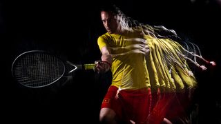 A stroboscopic flash portrait of a tennis player in a studio on a black background wearing a yellow shirt