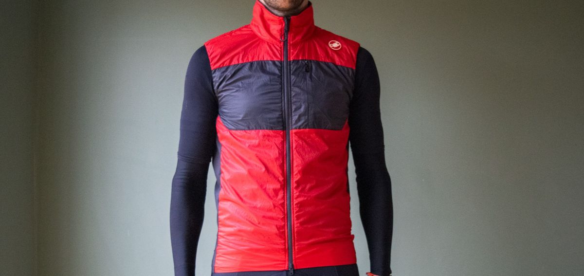 A male cyclist wearing a red Castelli Unlimited Puffy vest 