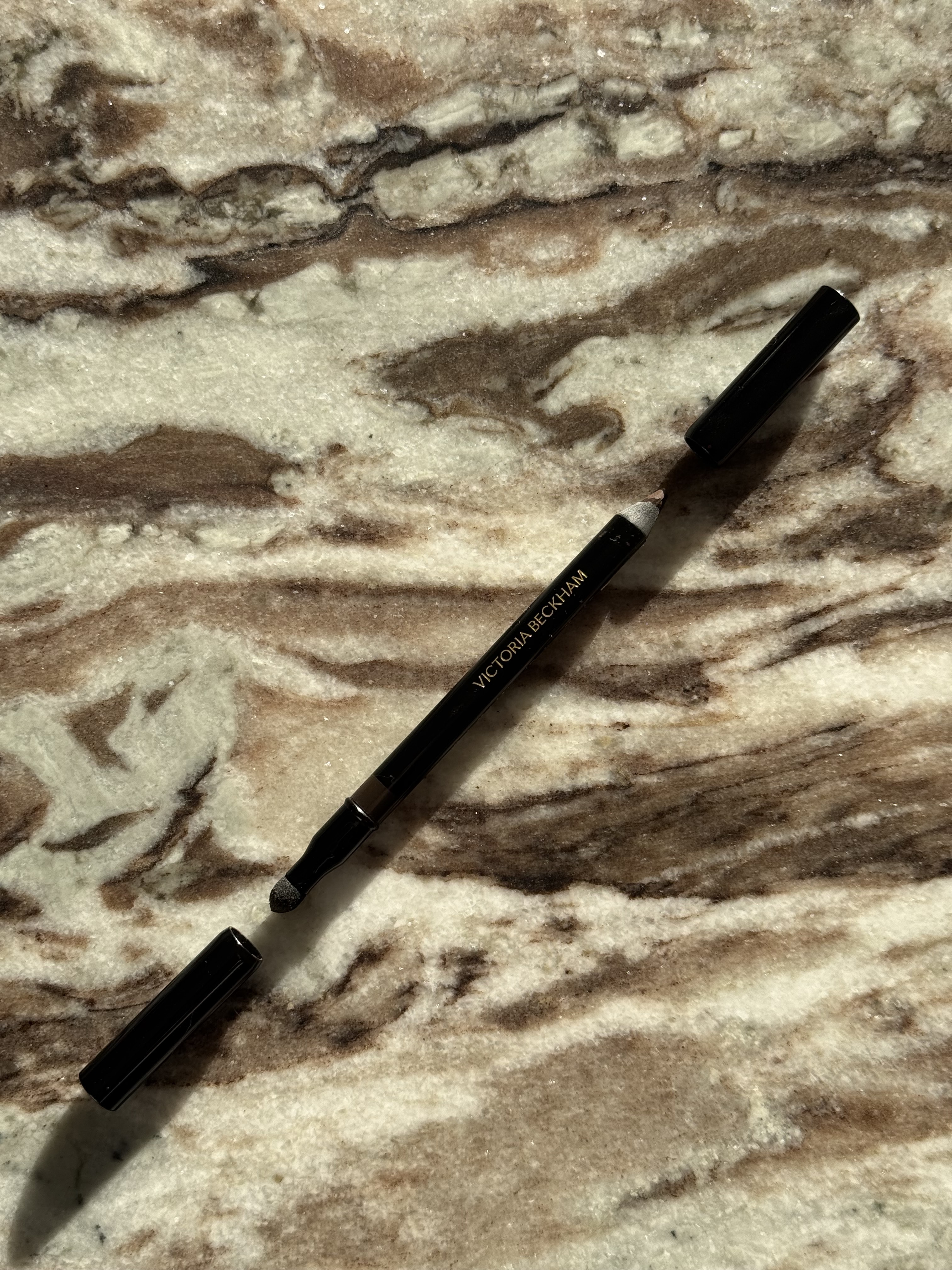The victoria beckham satin kajal liner in cocoa up close on a marble table