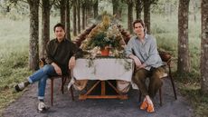 Alan Calpe and Christopher Crawford, founders of Gardenheir sitting at the end of a long dinner table on a tree-lined path