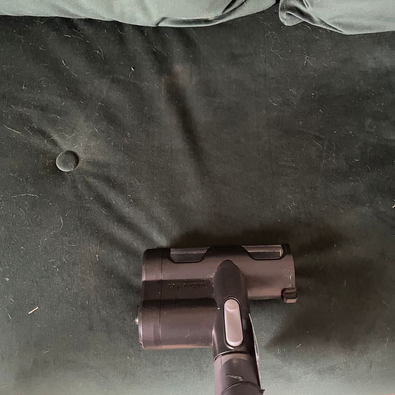 Using the pet tool of the Vax LiftOut Reach Pet Design Vacuum Cleaner to clean a green sofa bed