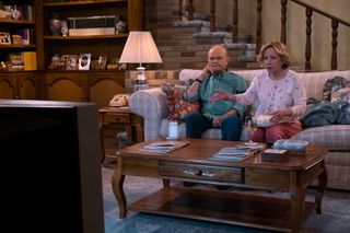 (L to R) Kurtwood Smith as Red Forman, Debra Jo Rupp as Kitty Forman sitting on the sofa watching TV in episode 104 of That ‘90s Show. Cr. Patrick Wymore/Netflix © 2022