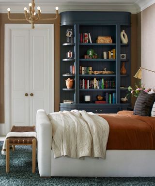 A bedroom with a white headboard, a built-in navy blue cabinet, and a wooden bench at the foot of the bed