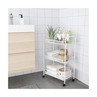 White bathroom trolley neatly organized with towels and bathroom essentials.