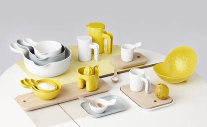 Ole Jensen's colourful tableware collection for Room Copenhagen. A range of white and yellow tableware on wooden cutting boards.