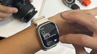 En vit Apple Watch Ultra runt en persons handled, där urtavlan visar klockans kvarstående batteri.