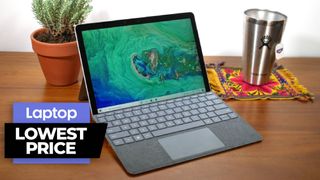 Surface Go 2 with keyboard propped on a wooden tablet next to a potted plant and stainless steel mug