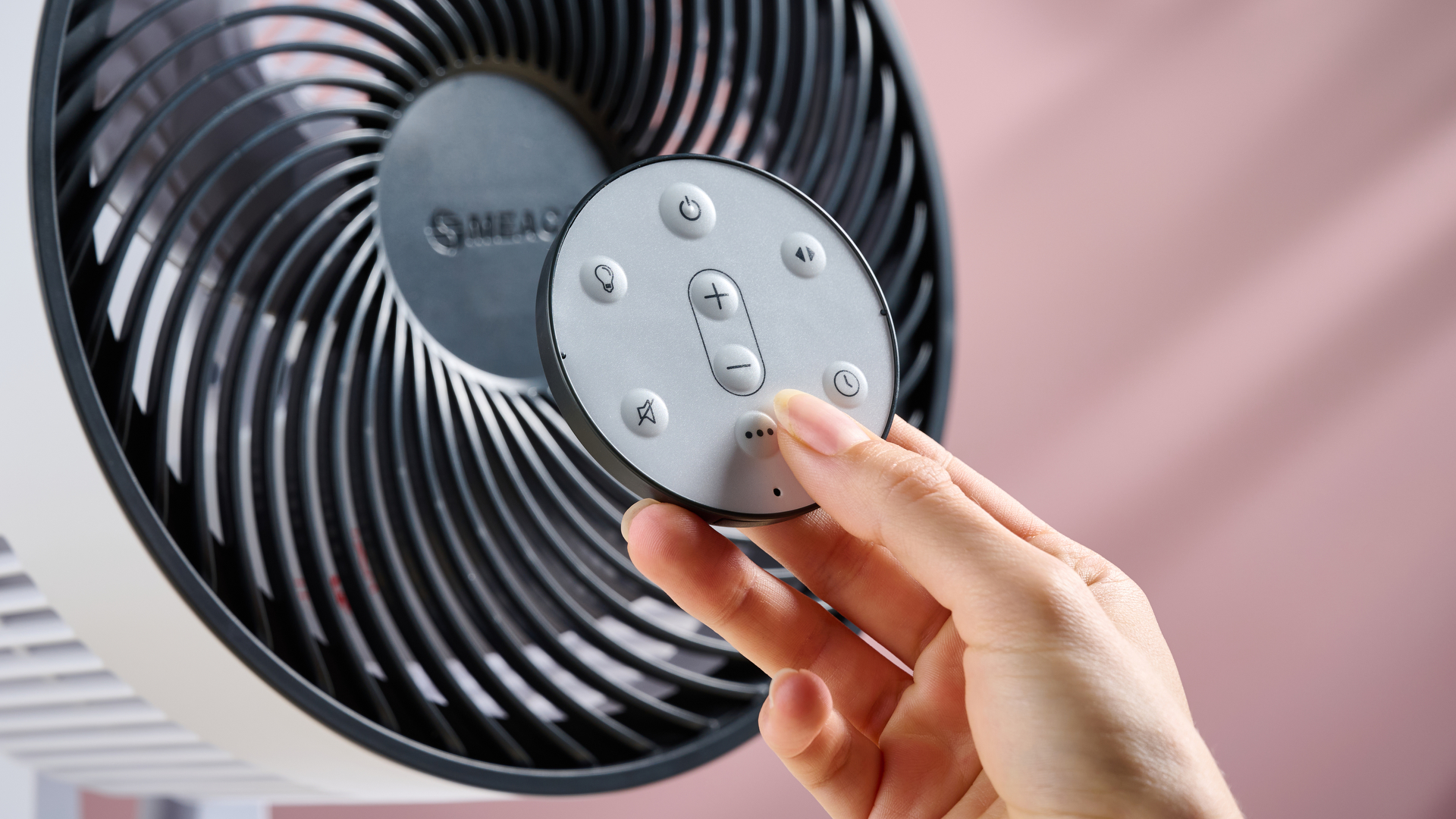 A woman is holding the circular remote control so the buttons are clearly visible.