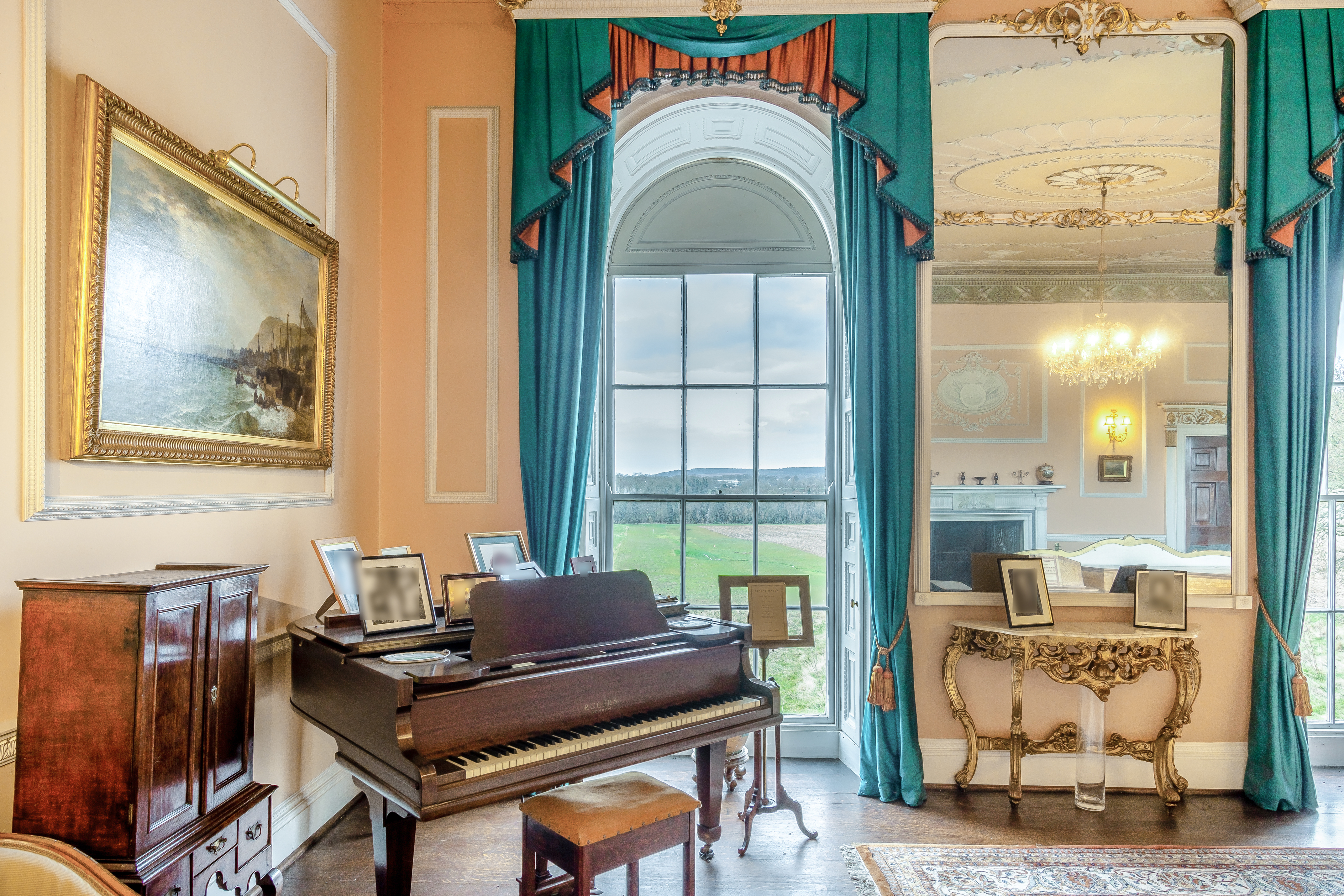 Teal curtains frame a large window beside an even larger mirror. There is also a grand piano
