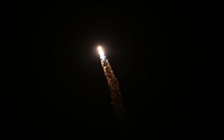 a fiery rocket launch streaks across a dark night sky