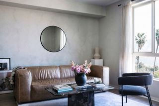 Living room with cool grey limewash walls, brown leather sofa and dark blue armchair