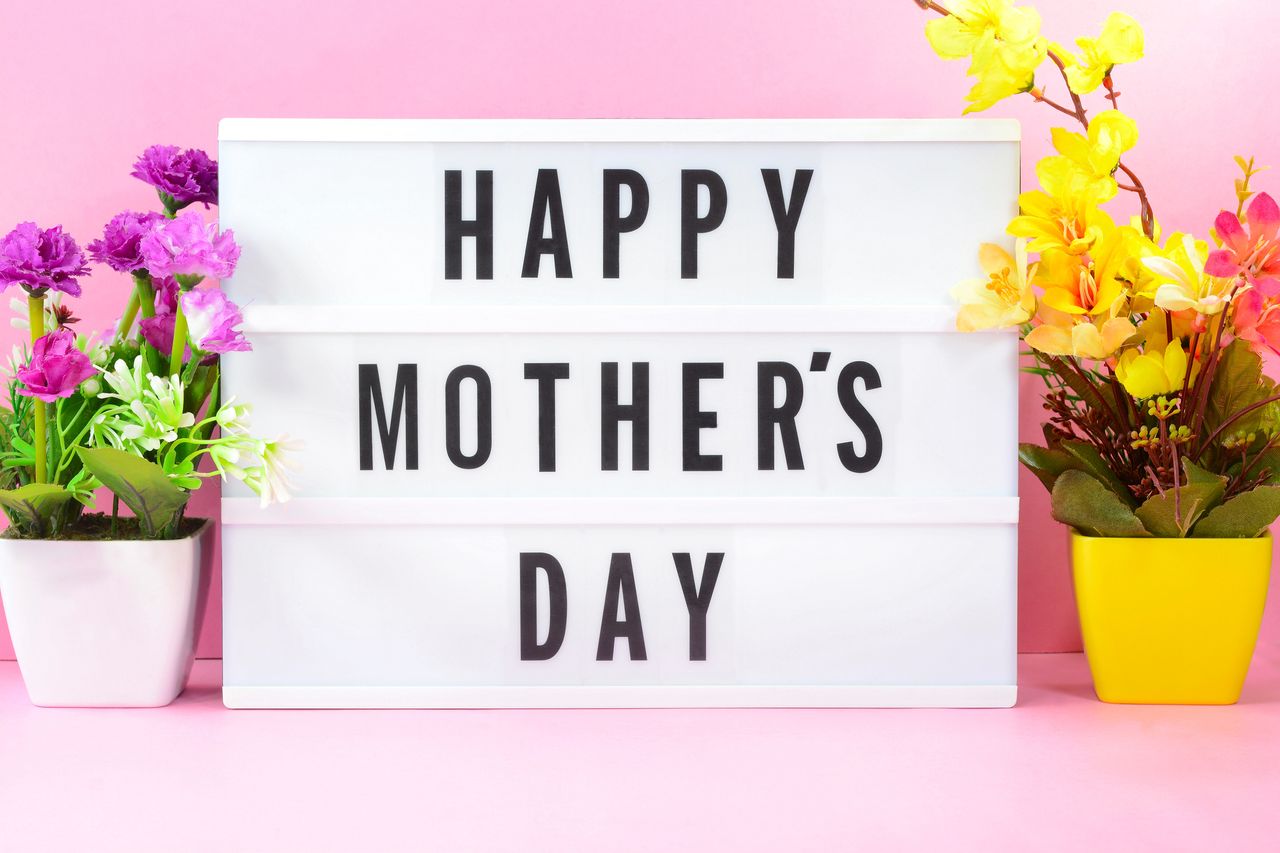 A lightbox with the words Happy Mother&#039;s Day, in front of a pink background with flowers.