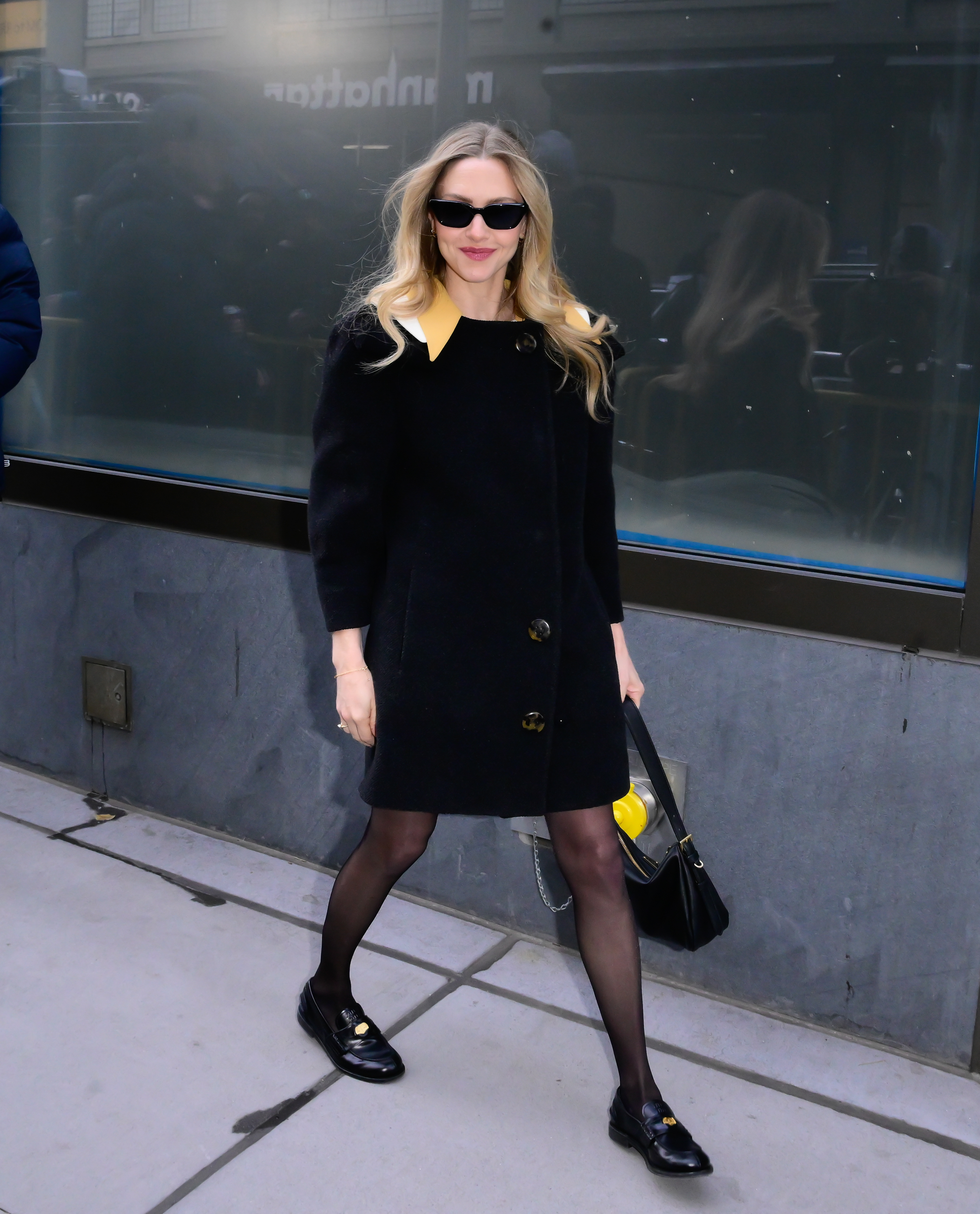 Amanda Seyfried wearing a black coat and Miu Miu loafers.