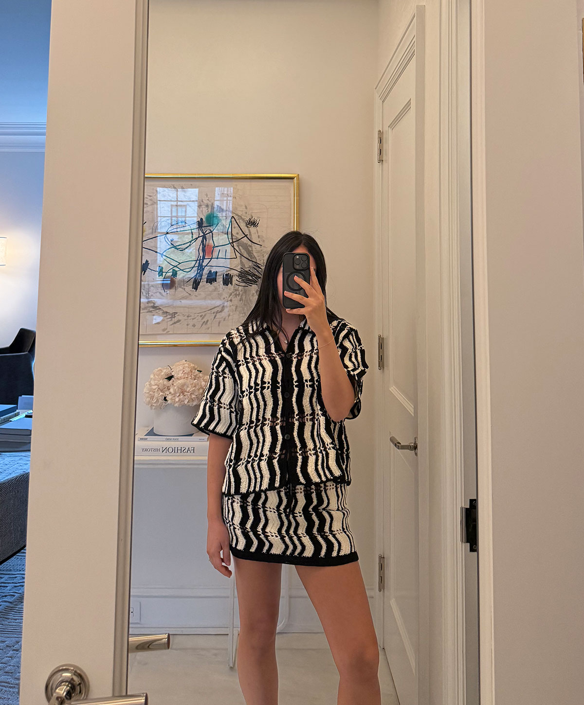 @nicoleakhtarzad taking a mirror outfit selfie and wearing a black and white crochet set.