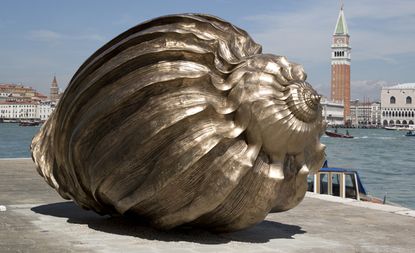 A large metal snail shell by a river