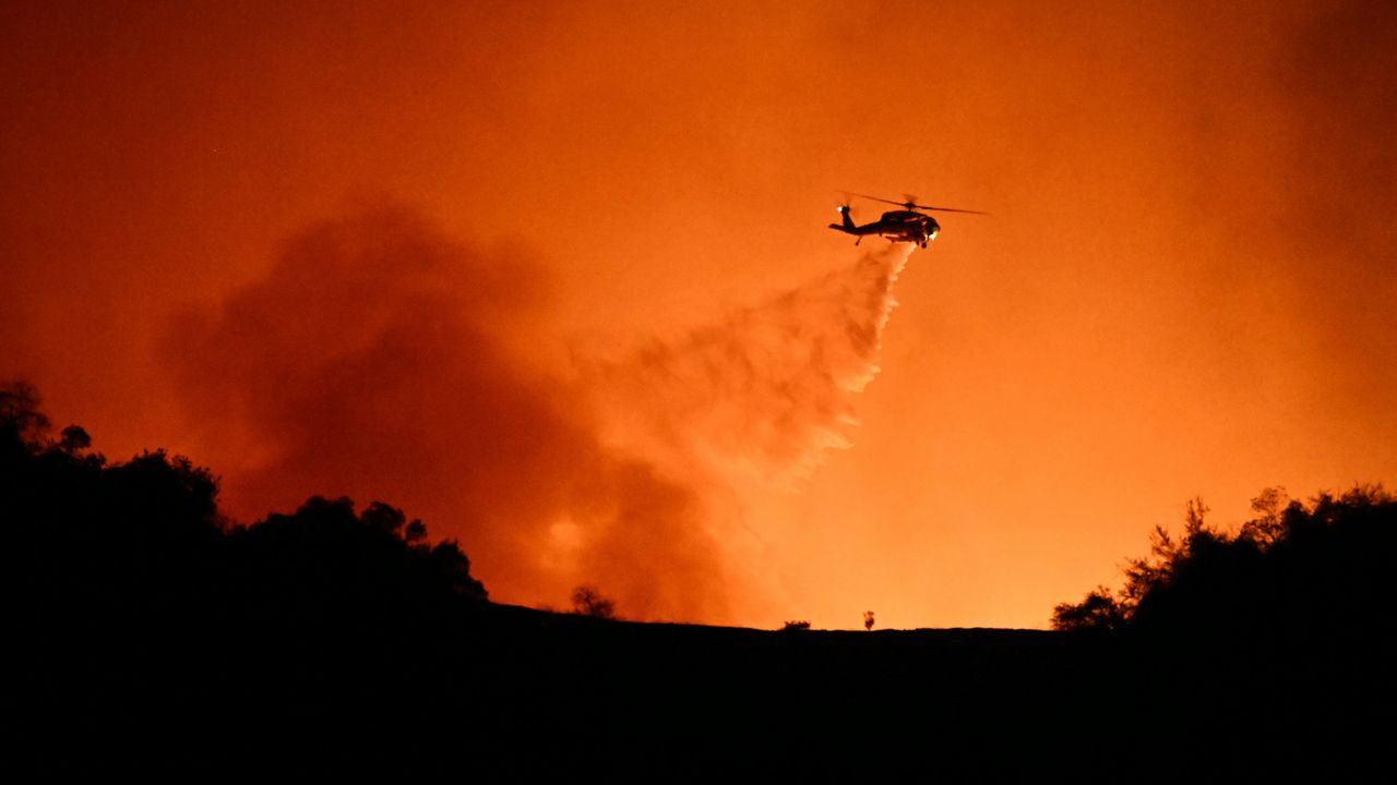 Firefighters in helicopter drop water on Los Angeles wildfire