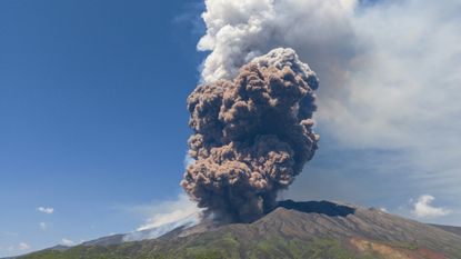 A photograph of Mount Etna erupting with a massive ash cloud on June 2, 2025. 