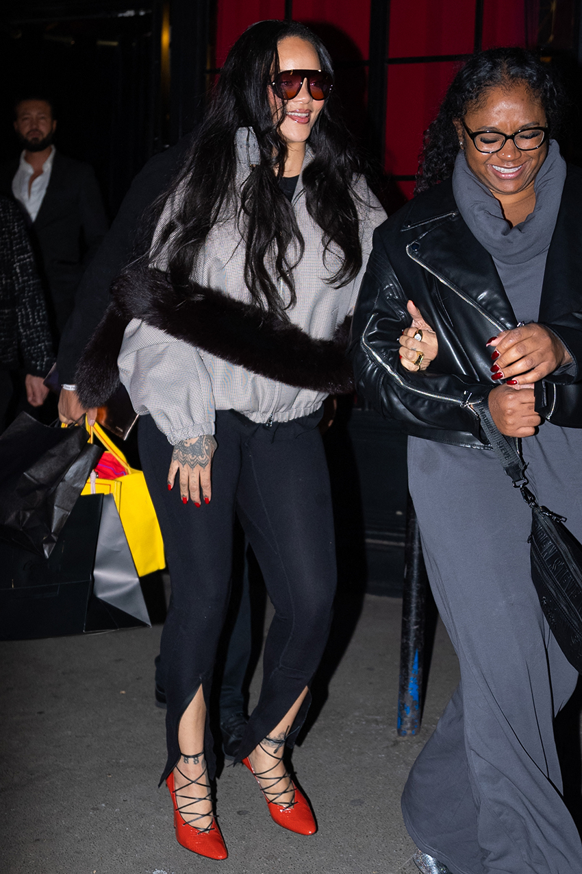 Rihanna wearing black sunglasses, plaid funnel neck jacket, slit leggings, and red lace up pumps