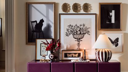 Items from Anthropologie Halloween collaboration with Catherine Martin, including a striped lamp, framed festive prints, sculptural cases, and brass candle holders.