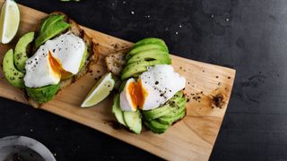 Poached eggs and avocado sitting on wooden chopping board