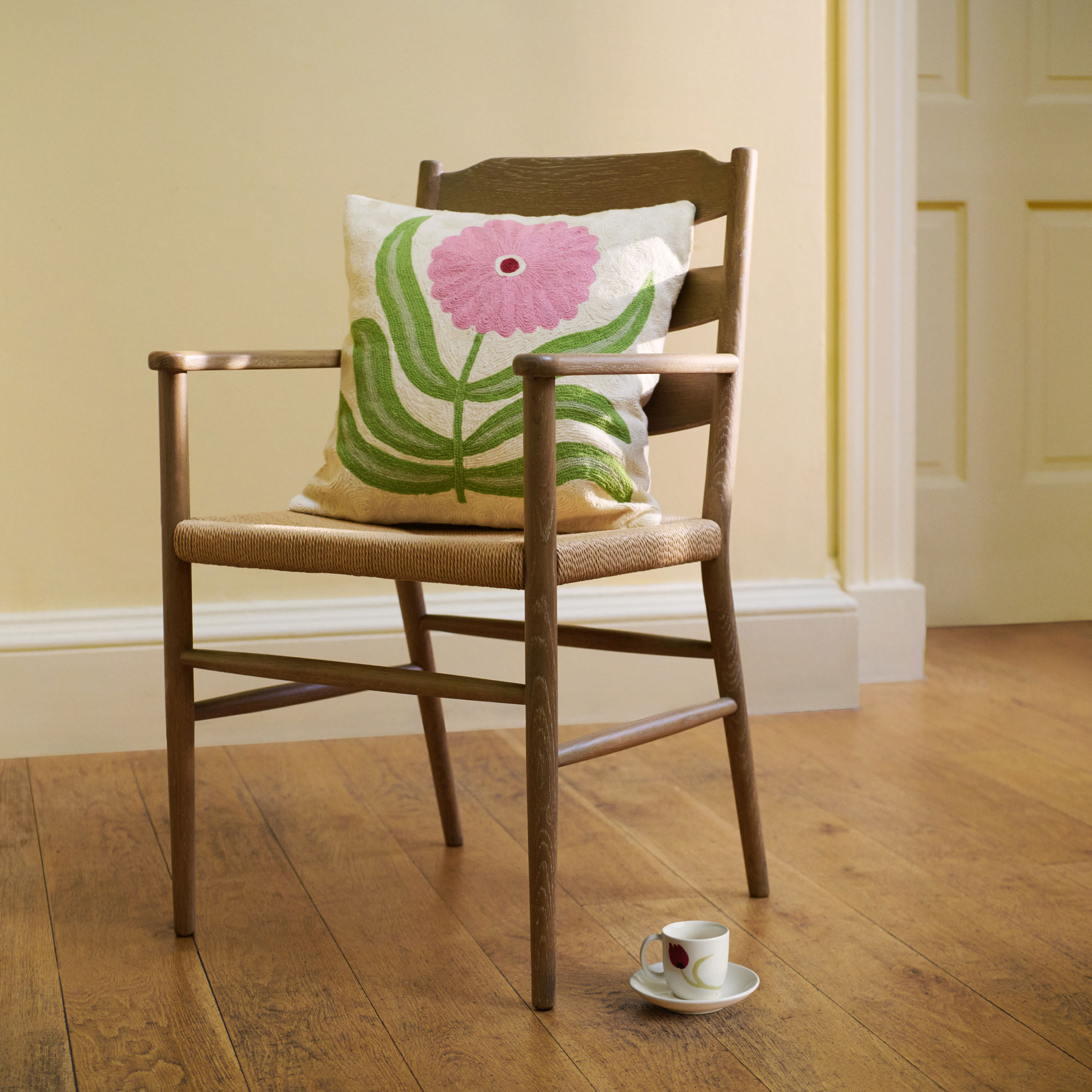 John Lewis Anine Cecile Iverson collection cushion showing a white background with green leaves and pink flower on a chair