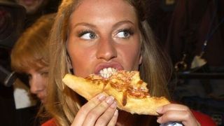 Gisele Bundchen eating a slice of pizza.