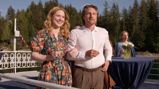 Mel and Jack in smart clothes looking into the distance with happy smiles on a boat for their pre-wedding dinner in Virgin River season 6