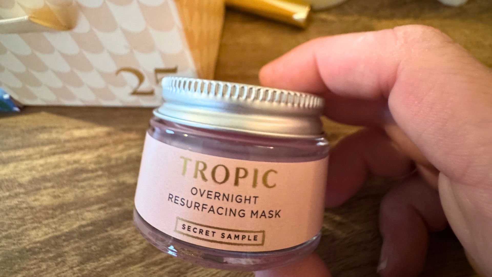 A person's hand holding the Tropic Overnight Resurfacing Mask from the 24 Days of Pure Imagination advent calendar