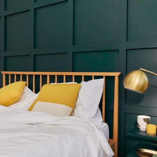 bedroom with teal wall panelling and brass lamp