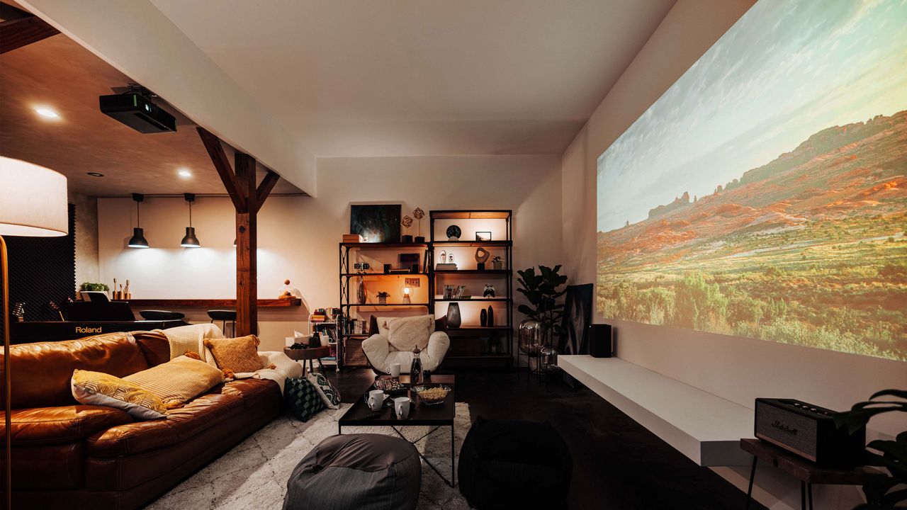 a projector in a basement living room with cosy sofas and a shelving unit against the wall