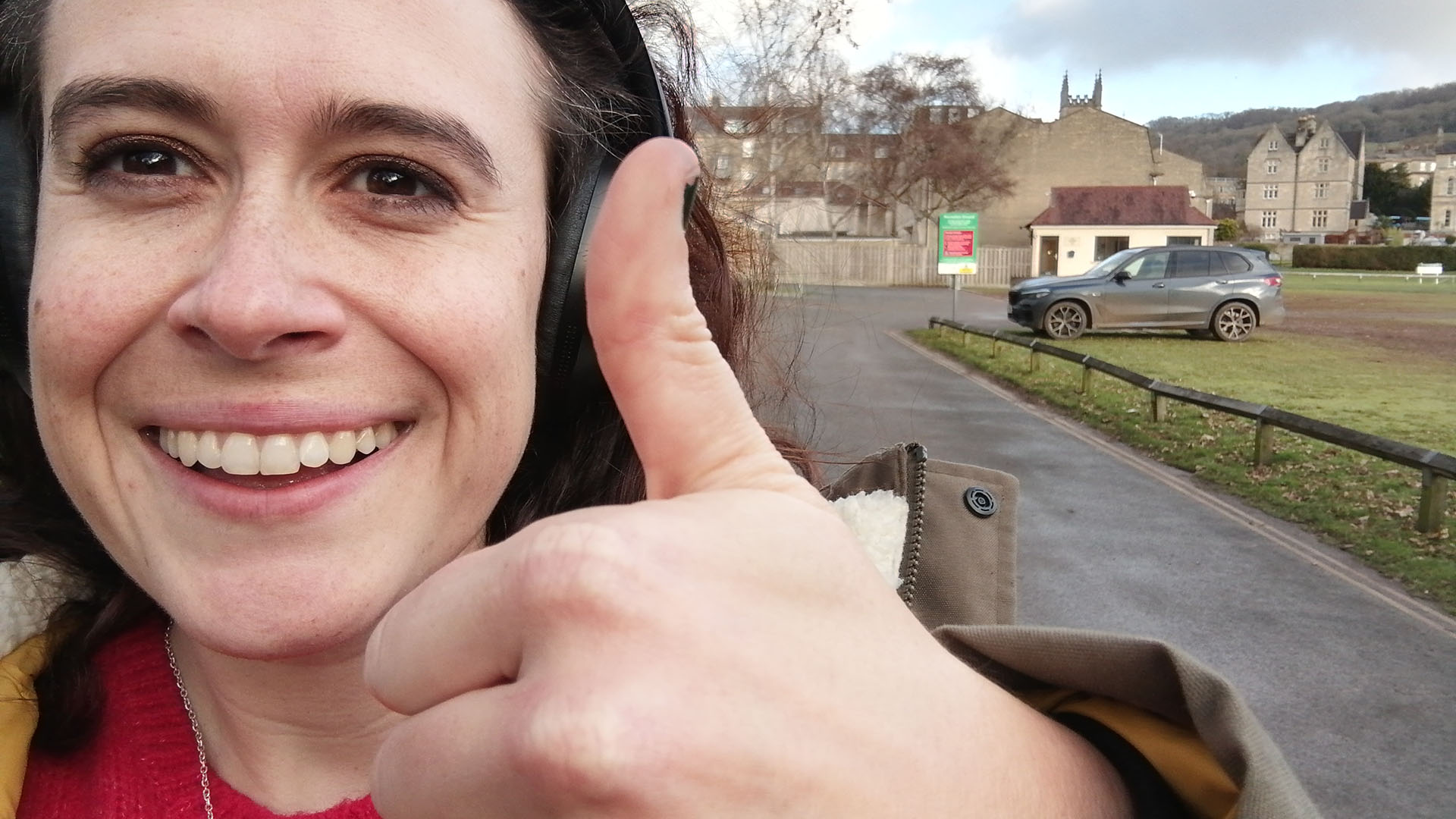 A person walking with a smile and wearing headphones