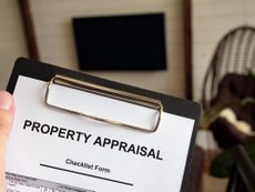 A person holding a property appraisal checklist on a clipboard. 