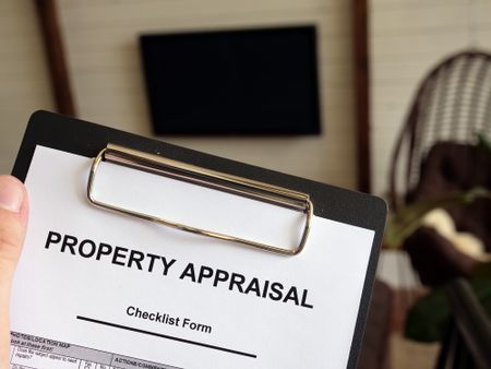 A person holding a property appraisal checklist on a clipboard. 