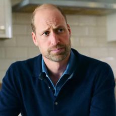 Prince William wearing a blue sweater sitting in a kitchen