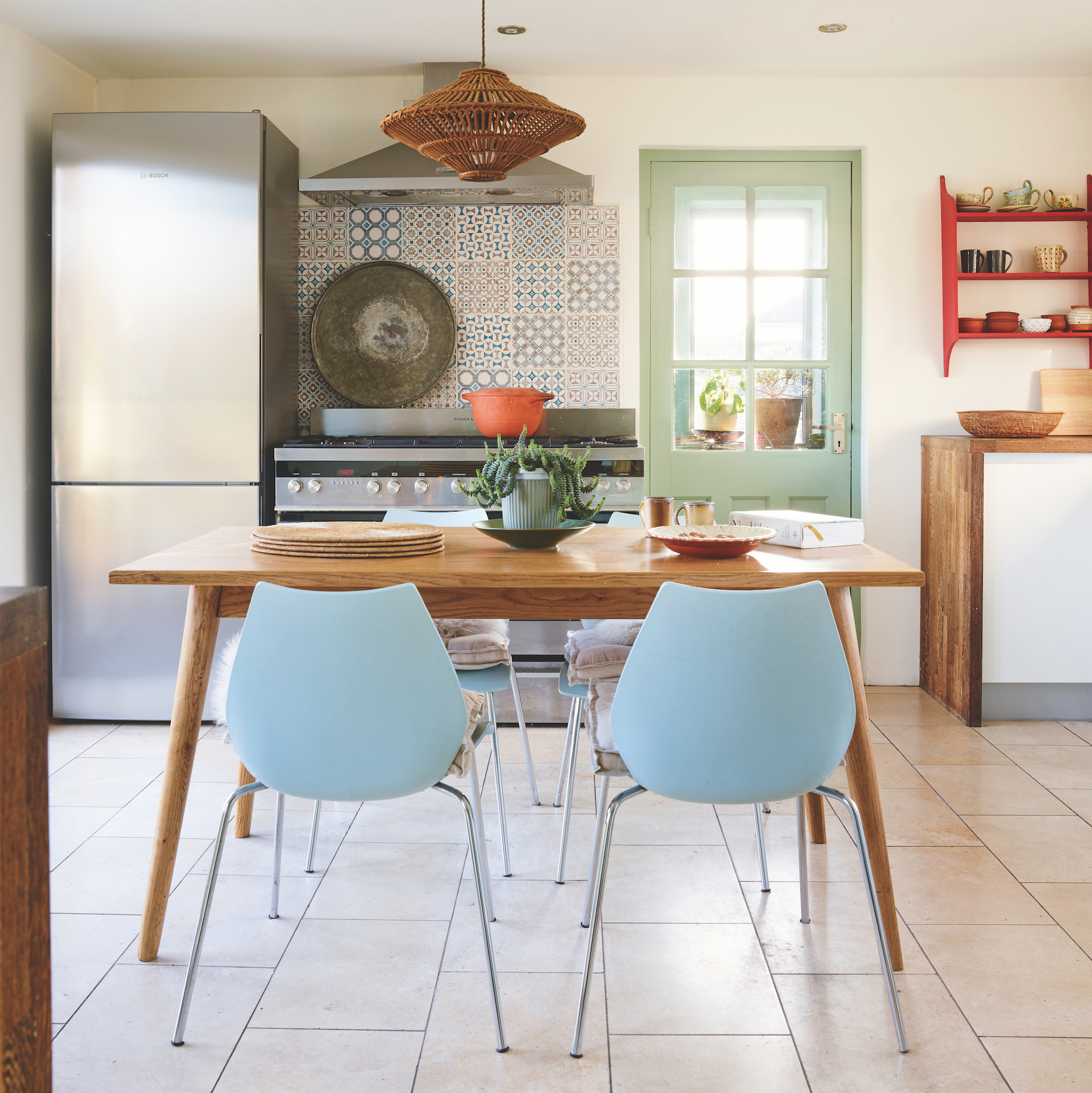 kitchen with wooden table and contemporary pale blue dining chairs, stainless steel range cooker with tiles above and stainless steel fridge