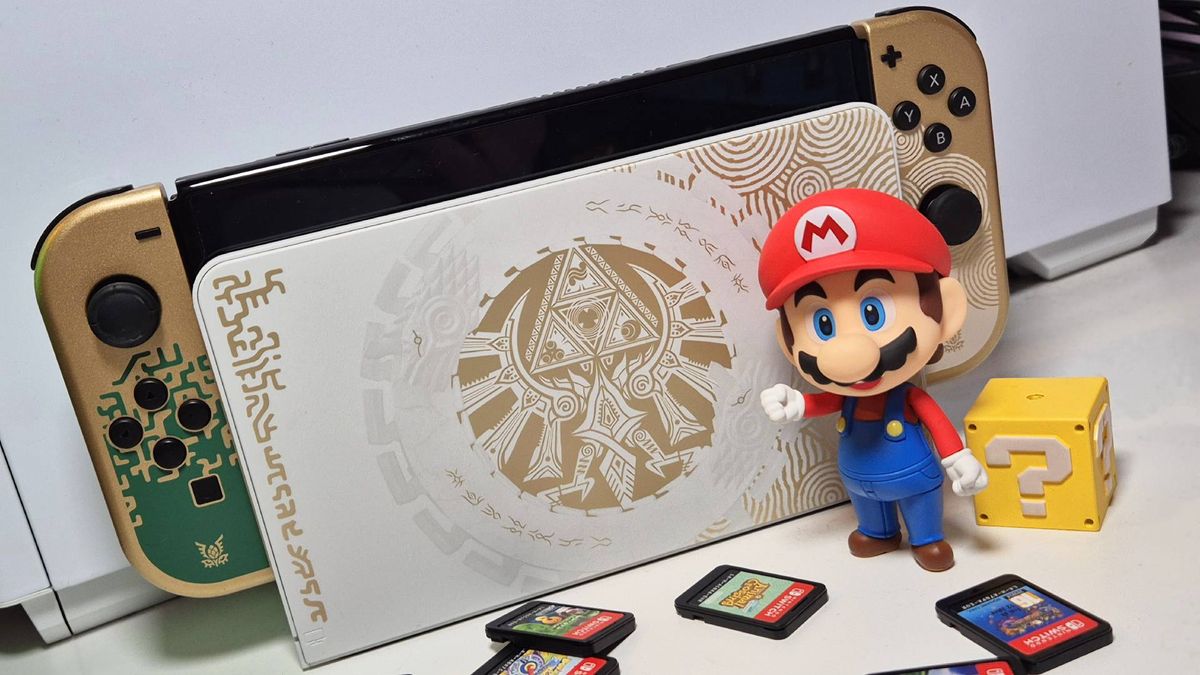 Photo taken by writer Rosalie Newcombe of the Tears of the Kingdom OLED Nintendo Switch handheld, with the Super Mario Nendoroid figure standing in front of it.