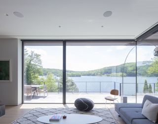 A minimalist living room with large windows with panoramic lake views