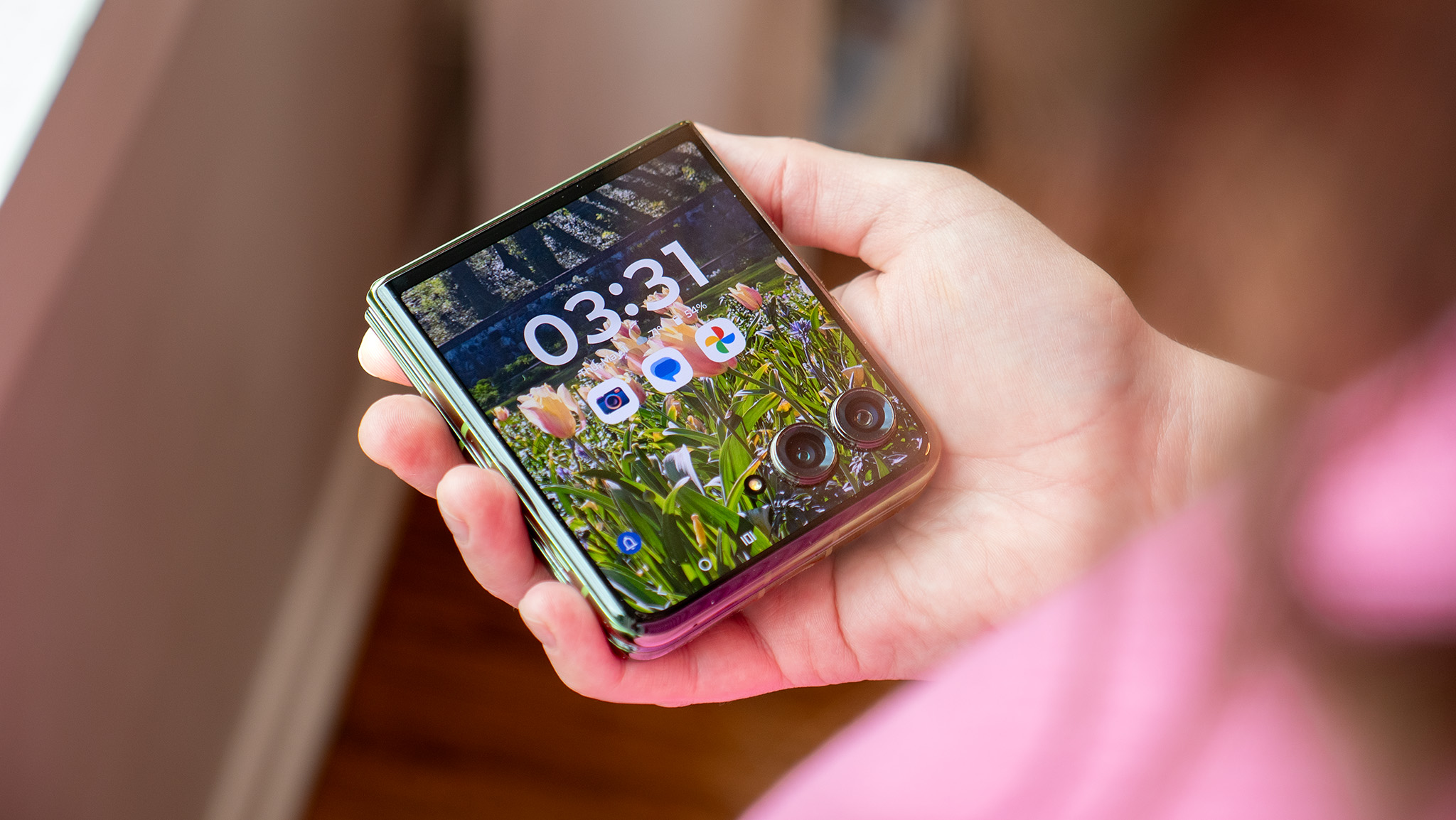 Holding a Motorola Razr Plus 2024 while it's closed with the cover screen illuminated and unlocked
