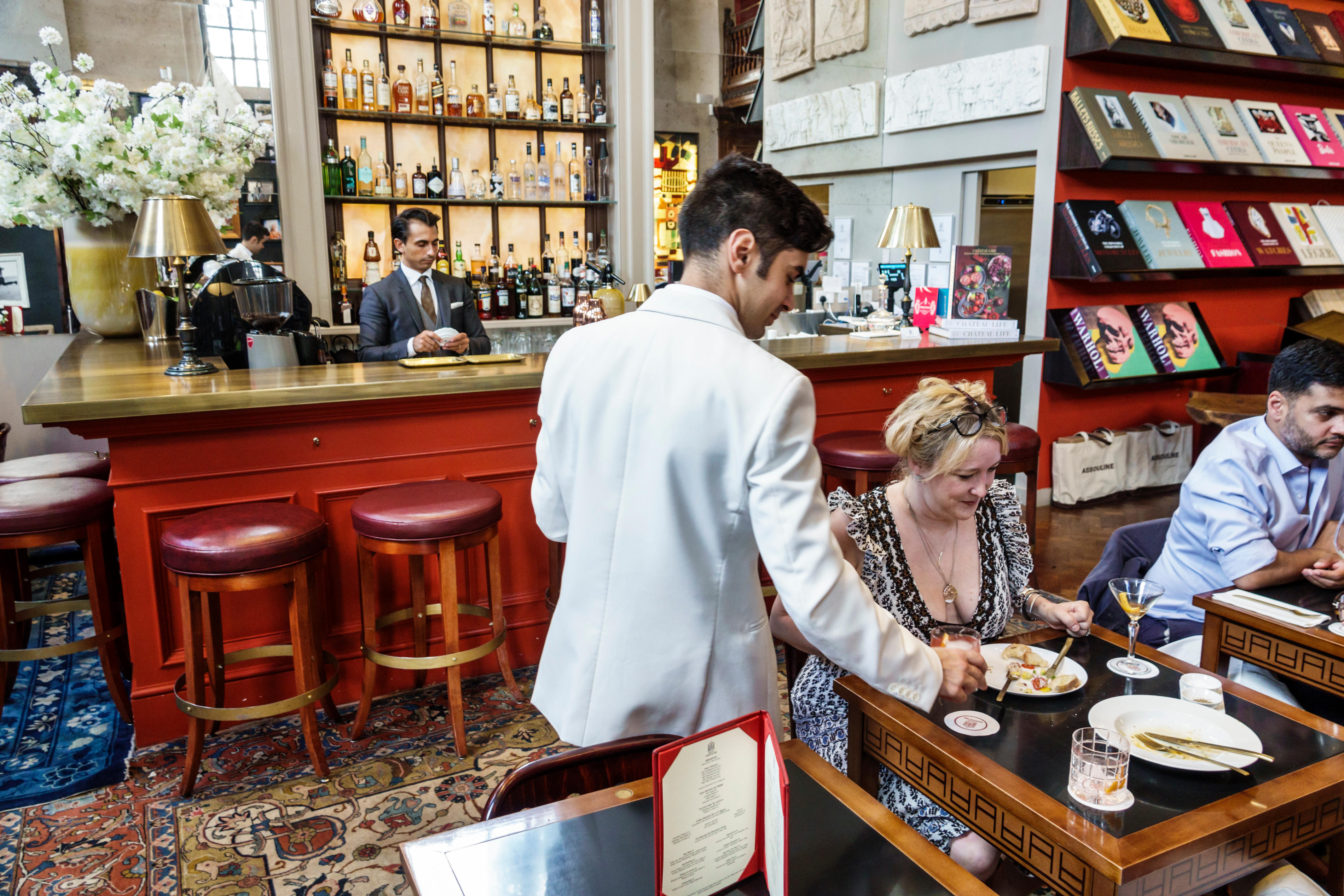 A man pours a cup of coffee to a patron eating breakfast in the coffee shop-cum-bookstore Maison Assouline