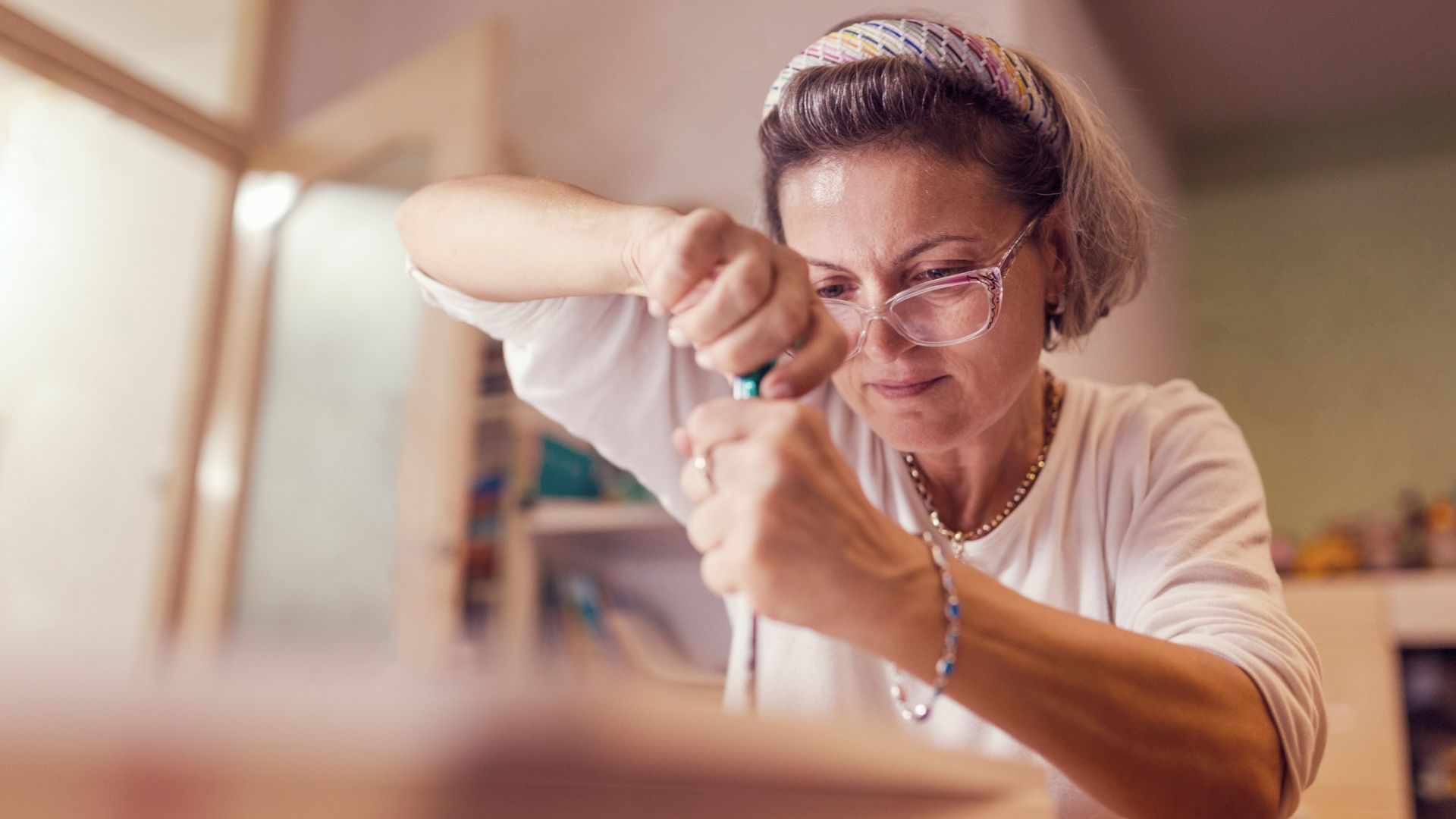 A woman gets to work fixing a piece of furniture