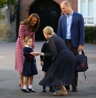 Helen Haslem, head of the lower school greets Princess Charlotte as she arrives for her first day of school, with her brother Prince George (hidden) and her parents the Duke and Duchess of Cambridge, at Thomas's Battersea in London on September 5, 2019 in London, England