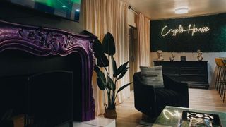 Crypto House; a room in a house with a neon sign and purple fireplace