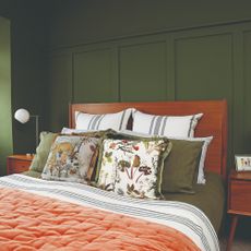 A colour-drenched dark green bedroom with shaker style wall panelling