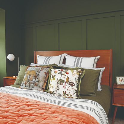 A colour-drenched dark green bedroom with shaker style wall panelling