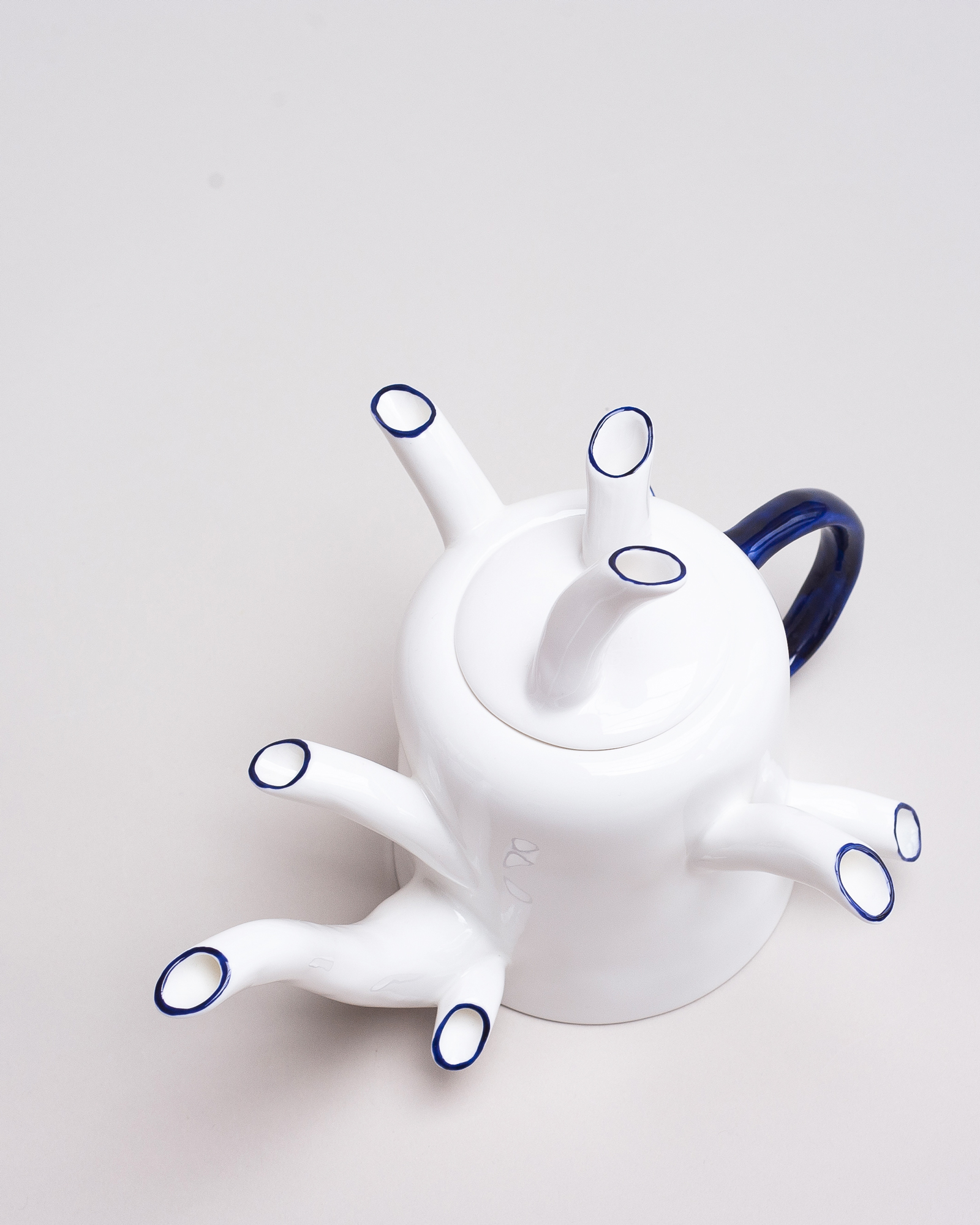 White bone china teapot with cobalt blue-painted handles and spouts